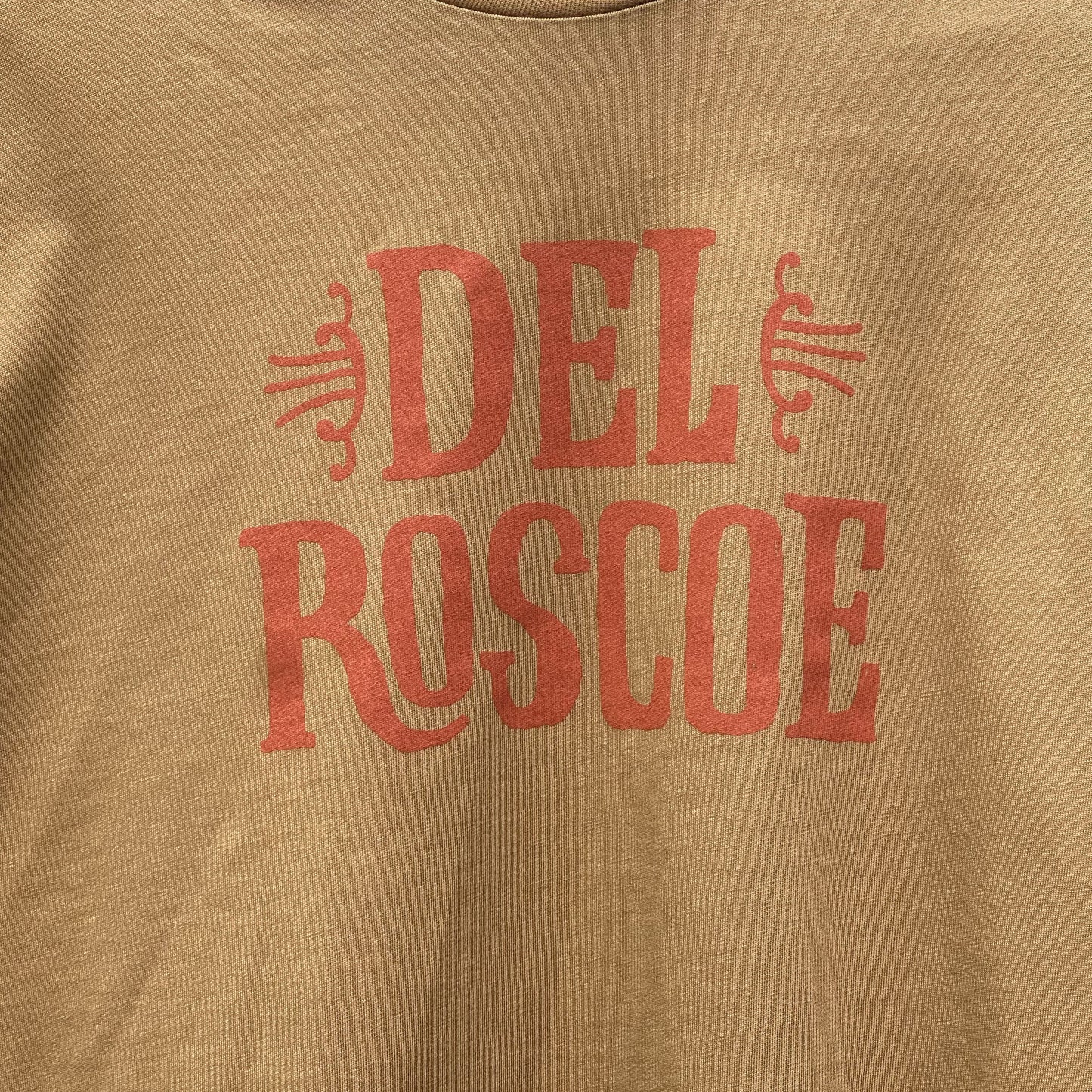 Camel color t-shirt with burnt orange 'Del Roscoe' text and logo