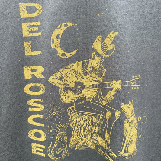Gray t-shirt with yellow graphic of a person playing guitar, surrounded by animals and celestial elements, on a gray background.